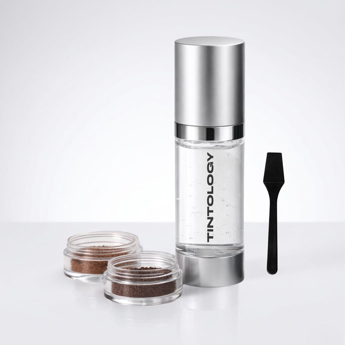 Tintology cosmetic product set with a bottle, applicator, and small containers on a white background