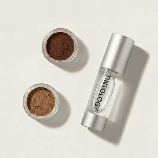 Two containers of brow powder and a silver bottle of Tintology activator brow gel on a light beige background.