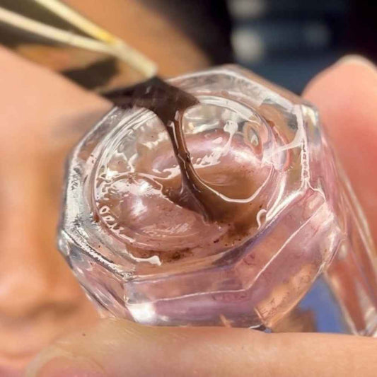 Close-up of brow makeup mixed on glass mixing dish.