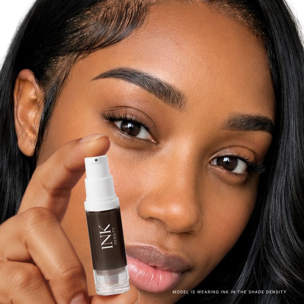 Model wearing INK brow pigment in shade DENSITY, holding the bottle to her face